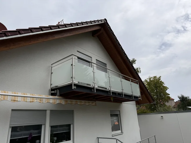 Balkongeländer aus Edelstahl mit satiniertem Glas an einem Giebelhaus