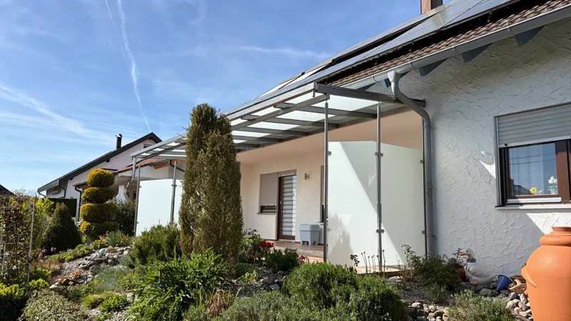 Terrassendach mit satiniertem Windschutzglas an einem Einfamilienhaus
